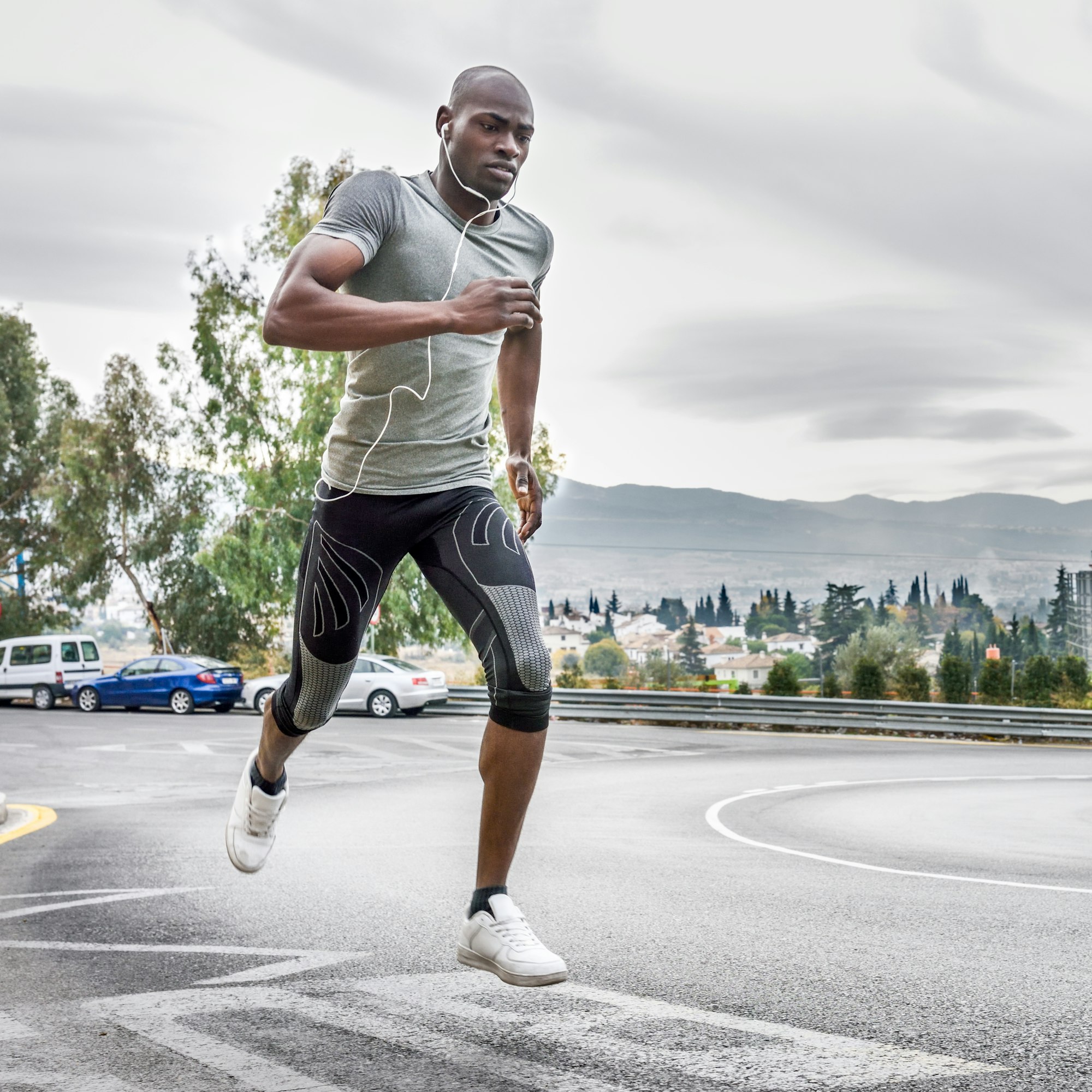 Black man running outdoors in urban road.