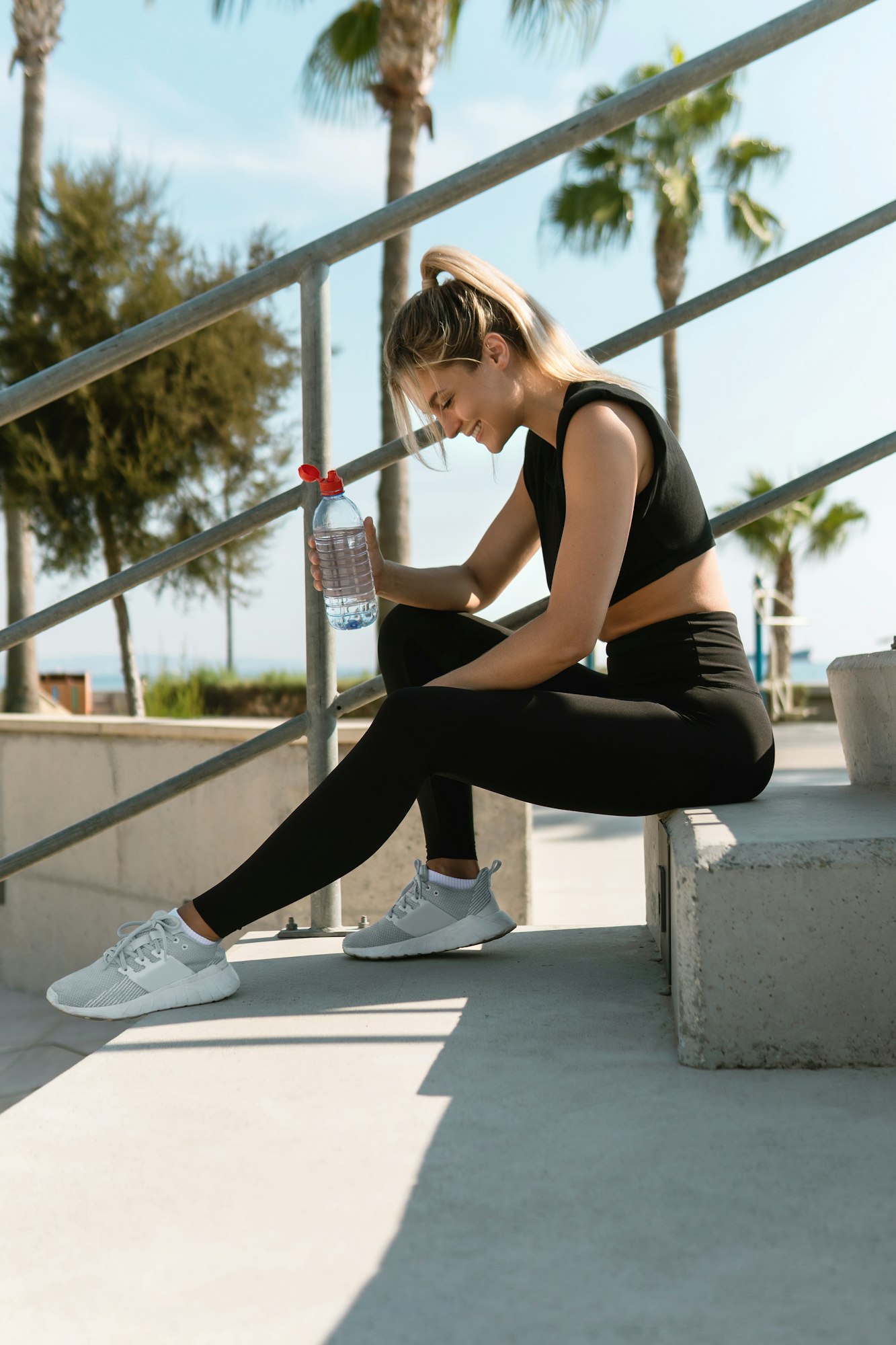 Happy woman drinking water after her summer workout